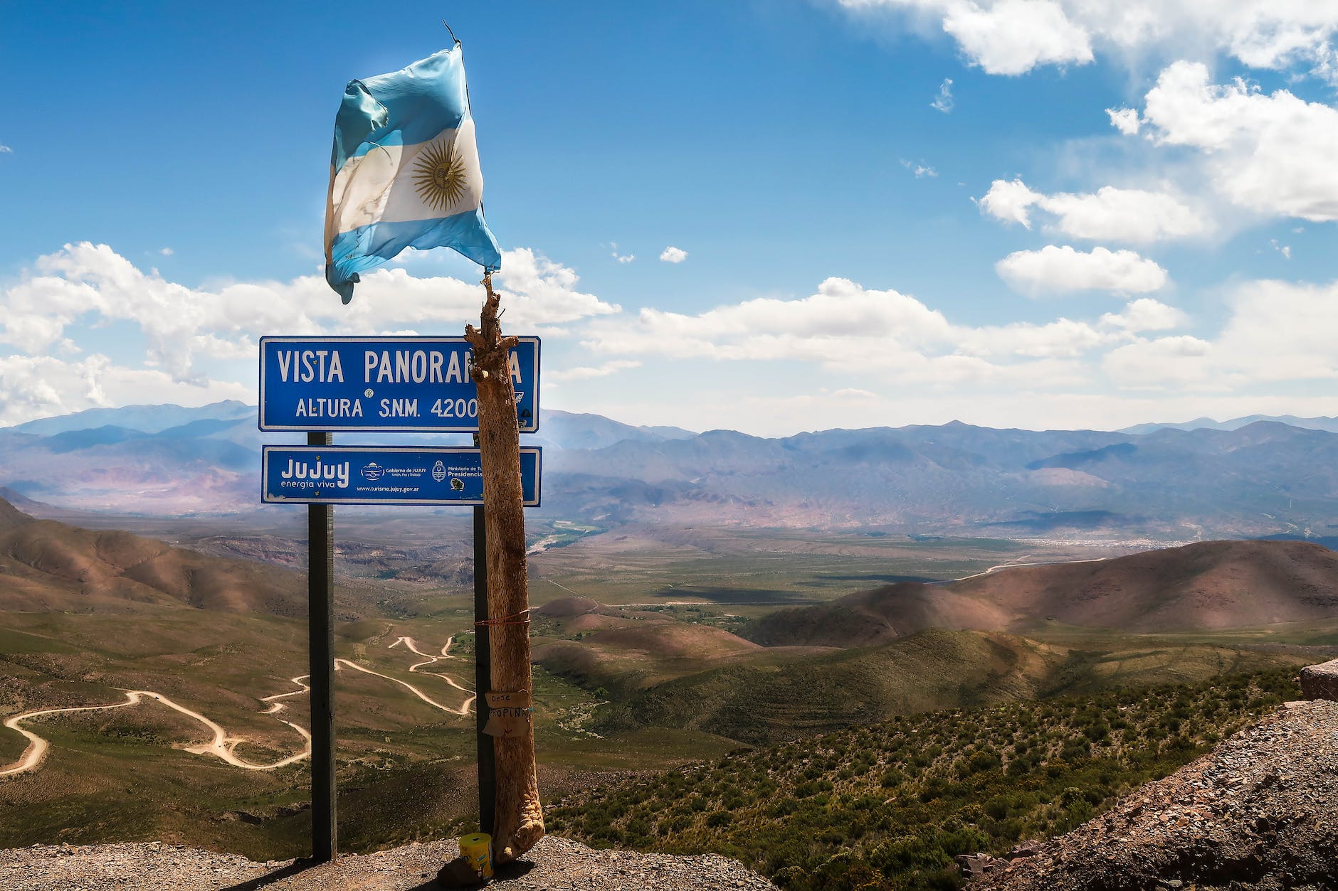 a flag and a sign with mountains in the background